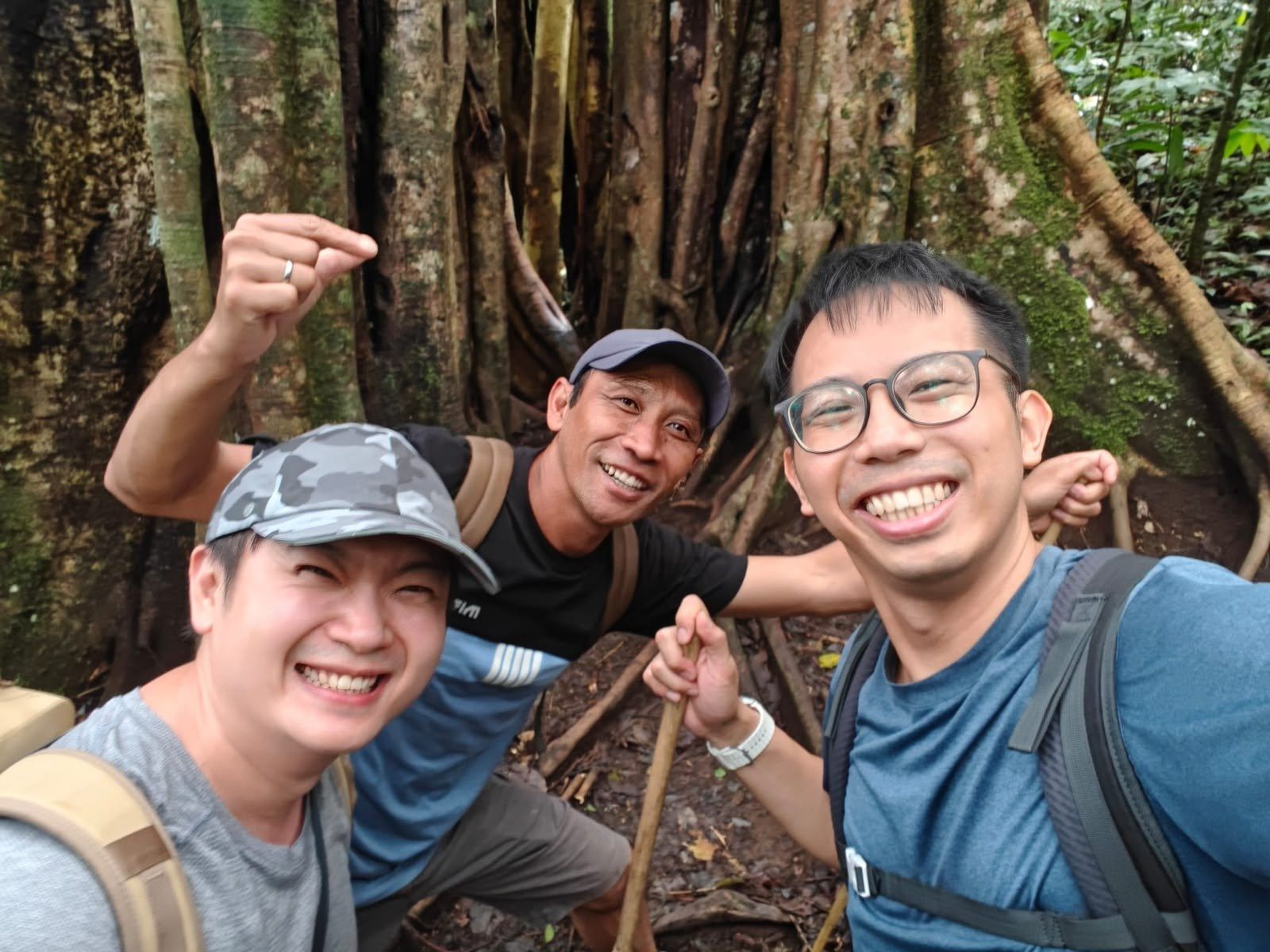 Guide and two hikers taking a selfie among banyan roots