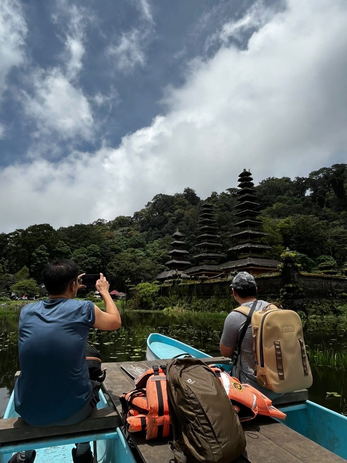 Hikers photographing the tiered shrines of Pura Ulun Danu Tamblingan from a canoe
